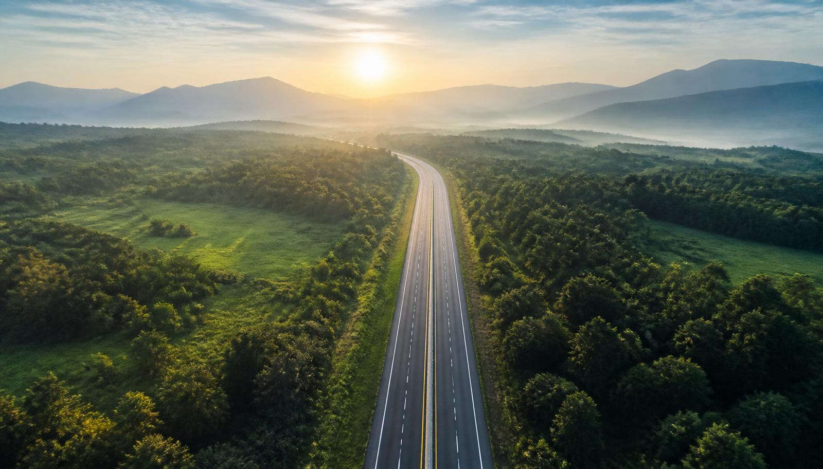 Clean highway through green landscape at sunrise